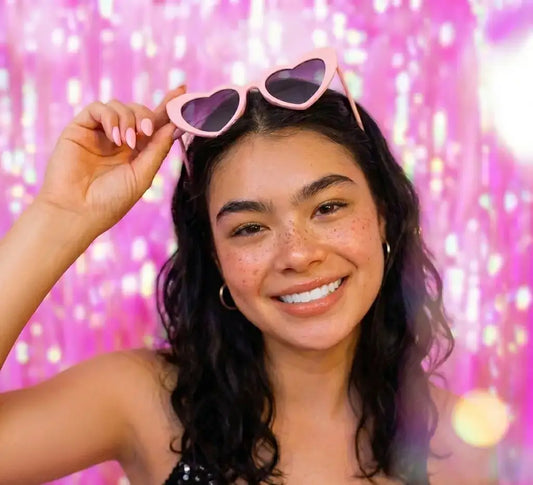 “Model wearing red heart shaped sunglasses for music festival outfit inspiration - Lover Era style.”