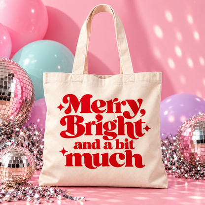 Natural organic cotton Christmas tote bag with bold red “Merry, Bright and a bit much” lettering and three decorative sparkles.