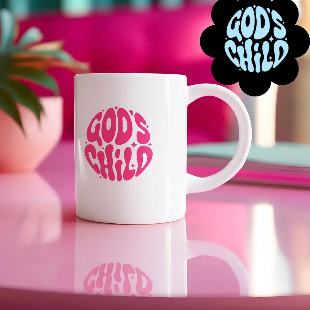 White mug with 'GOD'S CHILD' in pink on a reflective surface with a blurred background