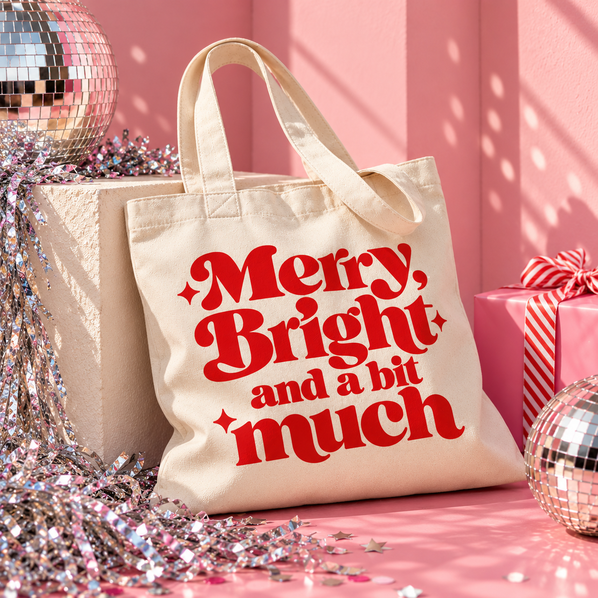 Natural organic cotton Christmas tote bag with bold red “Merry, Bright and a bit much” lettering and three decorative sparkles.