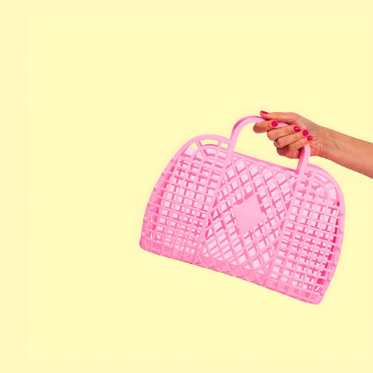 Hand holding a pink woven basket against a yellow background